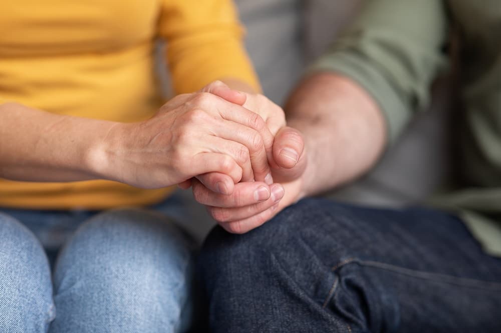 deux personnes qui se tiennent la main pour se soutenir après la mort d'un proche