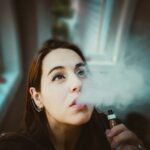 femme avec sa vapoteuse expirant de la vapeur de sa bouche