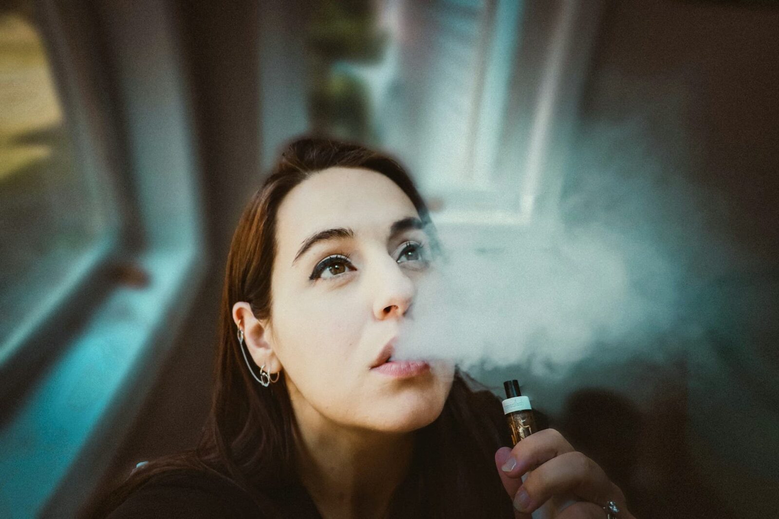 femme avec sa vapoteuse expirant de la vapeur de sa bouche