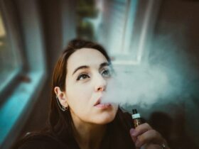 femme avec sa vapoteuse expirant de la vapeur de sa bouche