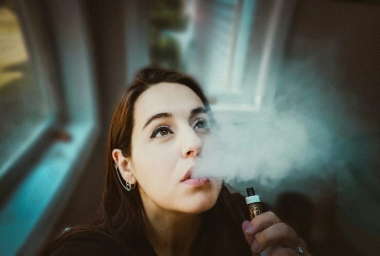 femme avec sa vapoteuse expirant de la vapeur de sa bouche